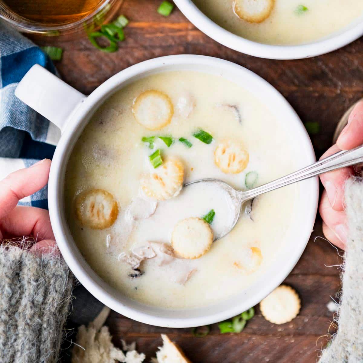 A person ladling oyster stew into bowls