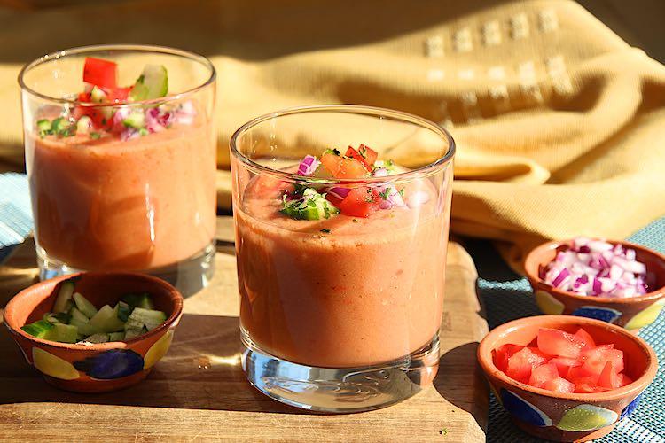 A person enjoying a bowl of gazpacho with rice outdoors
