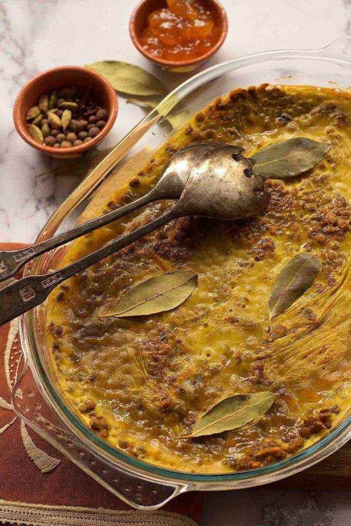 Close up shot of a spoon taking a bite of Bobotie, showing the texture and ingredients