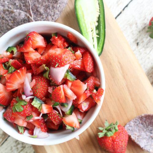 close up shot of vibrant strawberry jalapeno salsa in a glass bowl