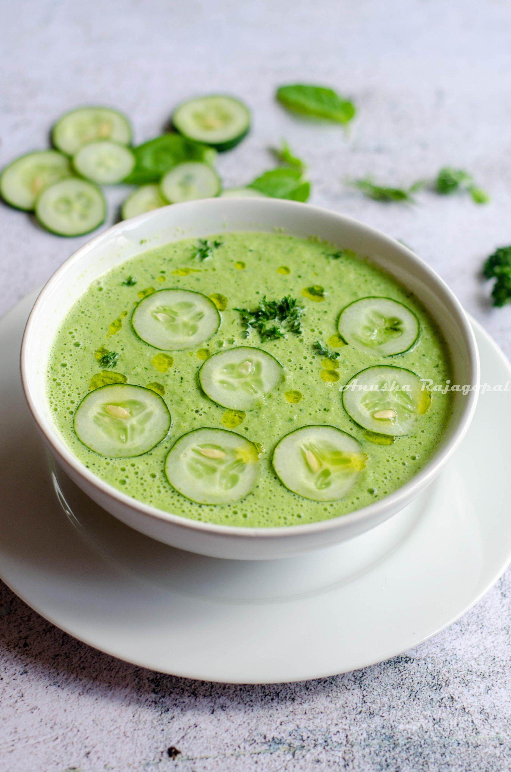 bowl of iced tomato and cucumber soup garnished with fresh herbs