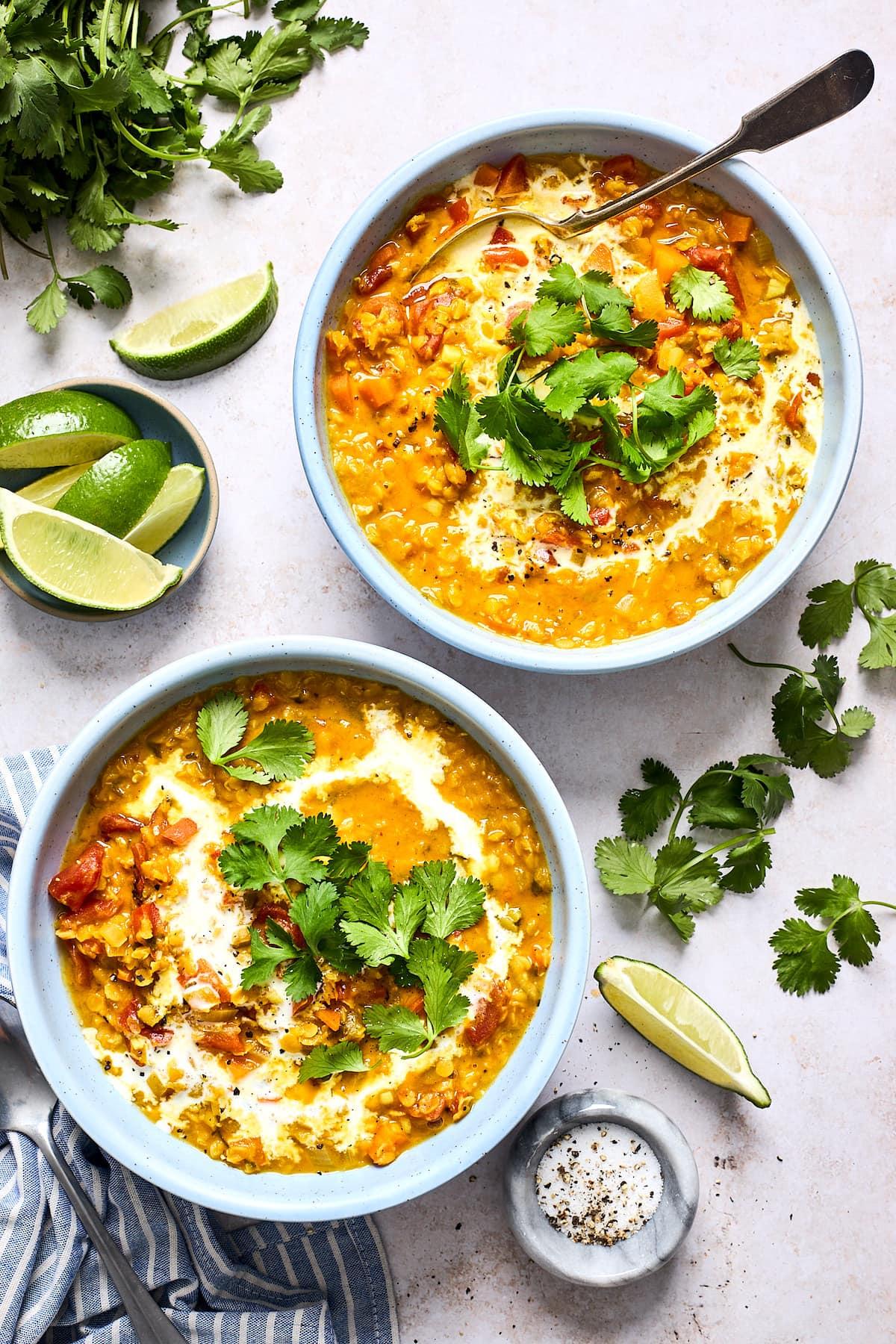 A person ladling South Asian lentil soup into bowls