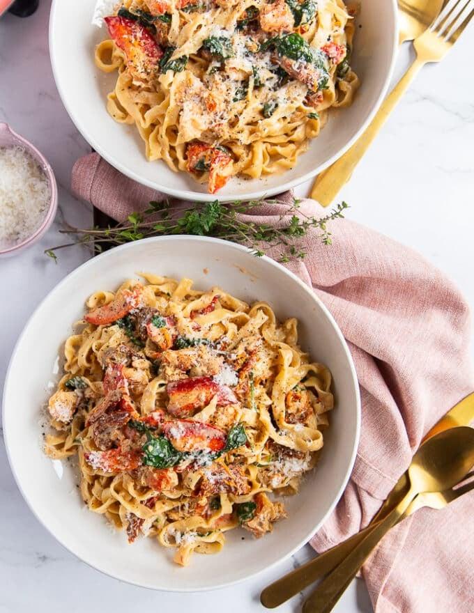 Creamy lobster pasta with sun-dried tomatoes, garnished with fresh parsley