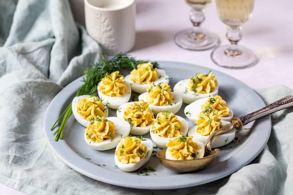 A platter of truffle deviled eggs with parmesan crisps, garnished with fresh herbs
