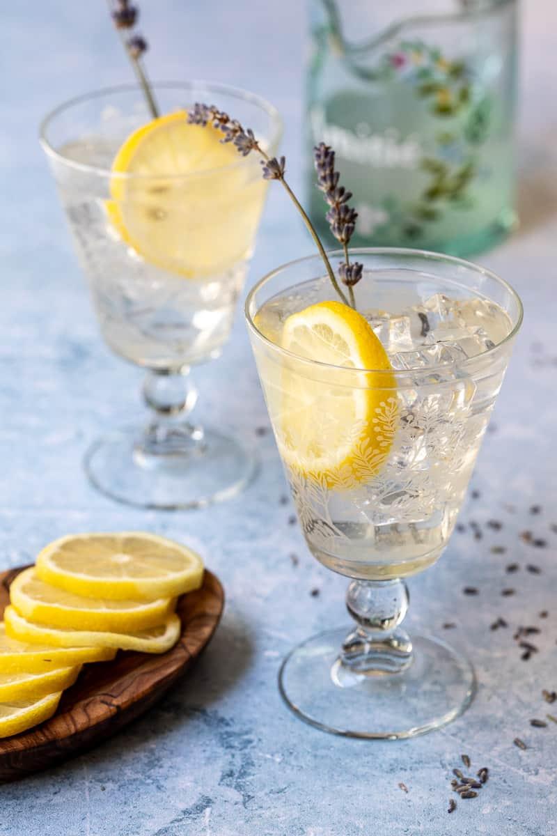 Glass pitcher of homemade lemon and lavender lemonade garnished with lemon slices and lavender sprigs