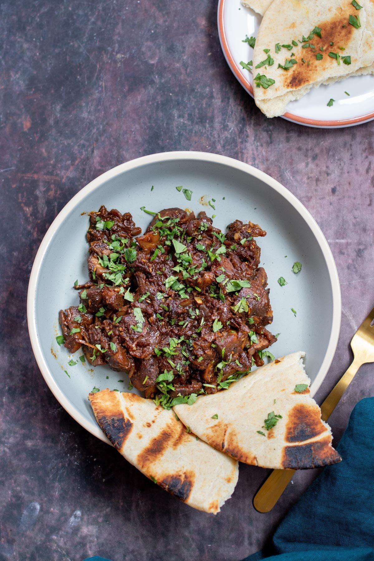 A plate of injera topped with sauteed mushrooms and onions