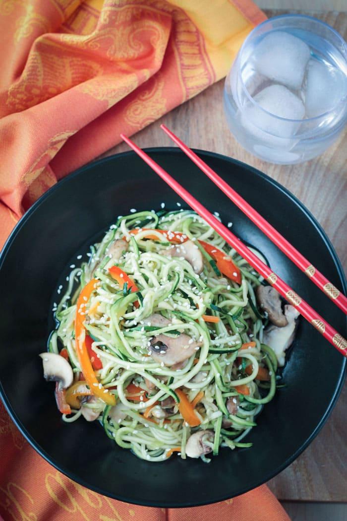 A person enjoying a bowl of zucchini noodle stir-fry