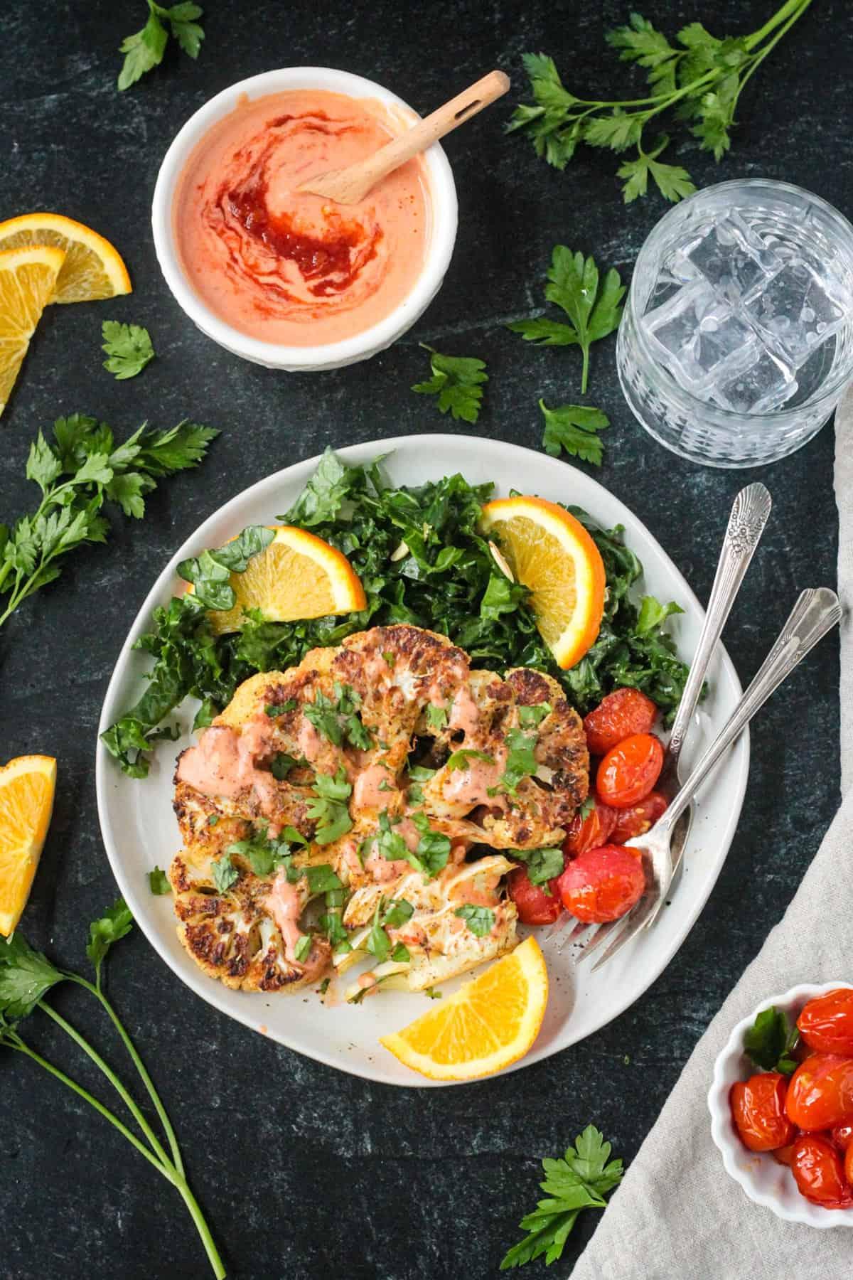 A plate of Za'atar Roasted Cauliflower Steaks garnished with parsley and a lemon wedge