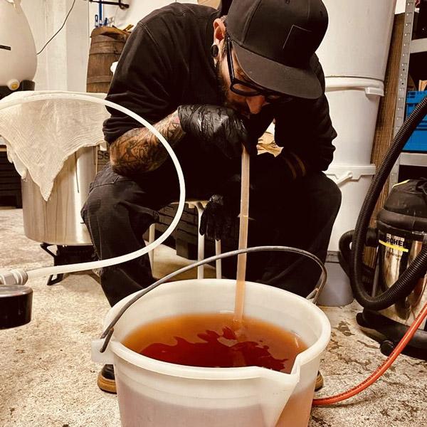 A person preparing the Kombucha Old Fashioned with Smoked Sugar