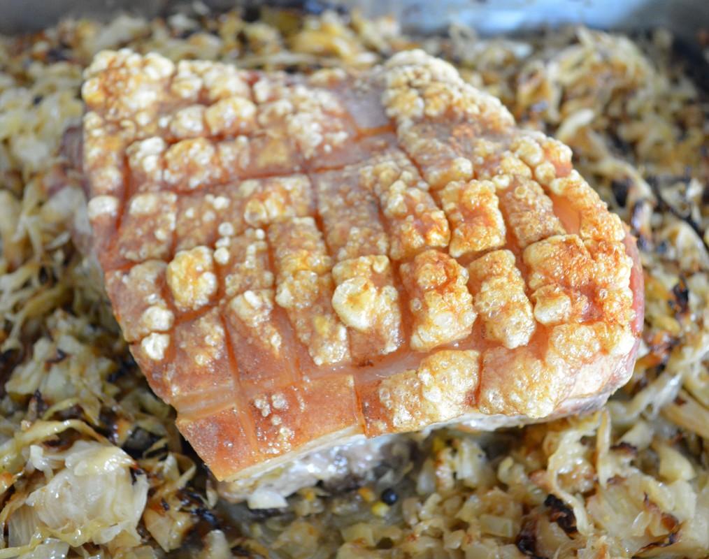 A close-up shot of the sauerkraut glaze bubbling on the pork belly during the baking process
