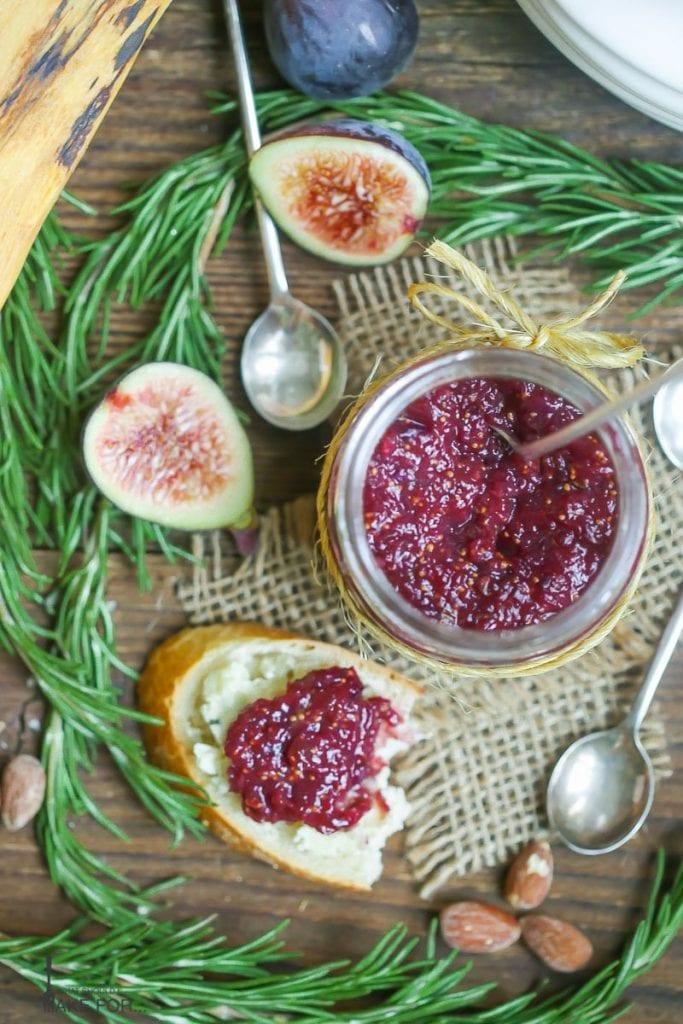Close-up shot of a spoonful of lingonberry and fig jam being spread on a biscuit
