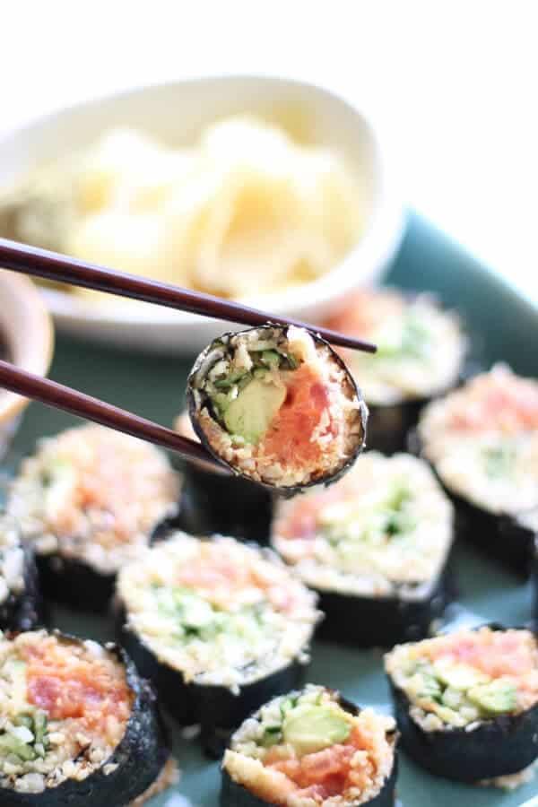 A person carefully rolling a piece of cauliflower rice sushi