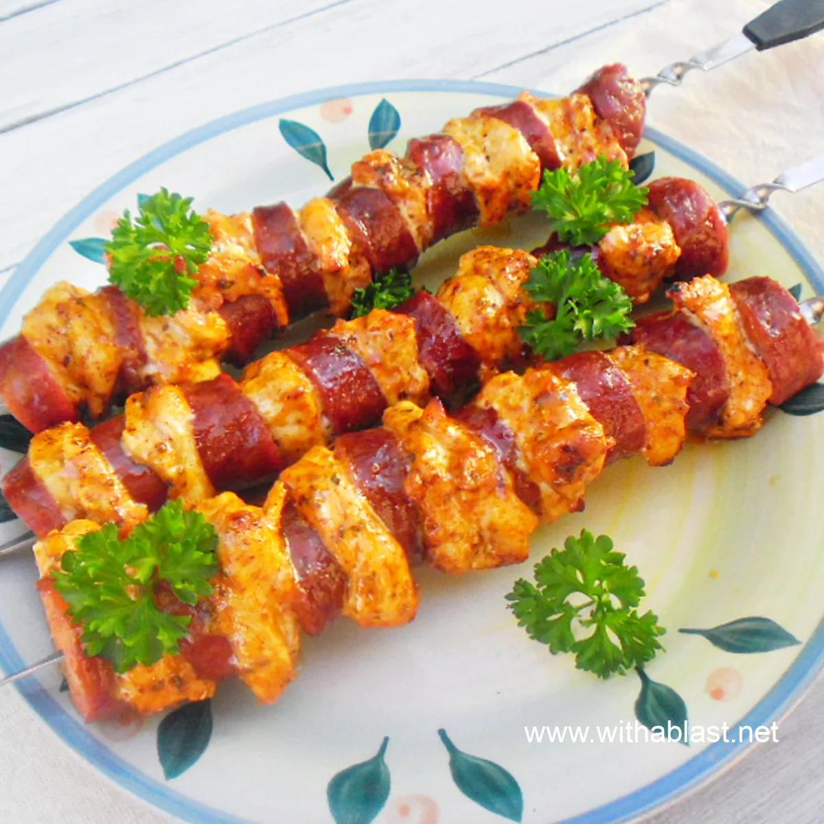 Close-up of chicken and chorizo kebabs grilling on a barbecue, showing the smoky char and vibrant colors