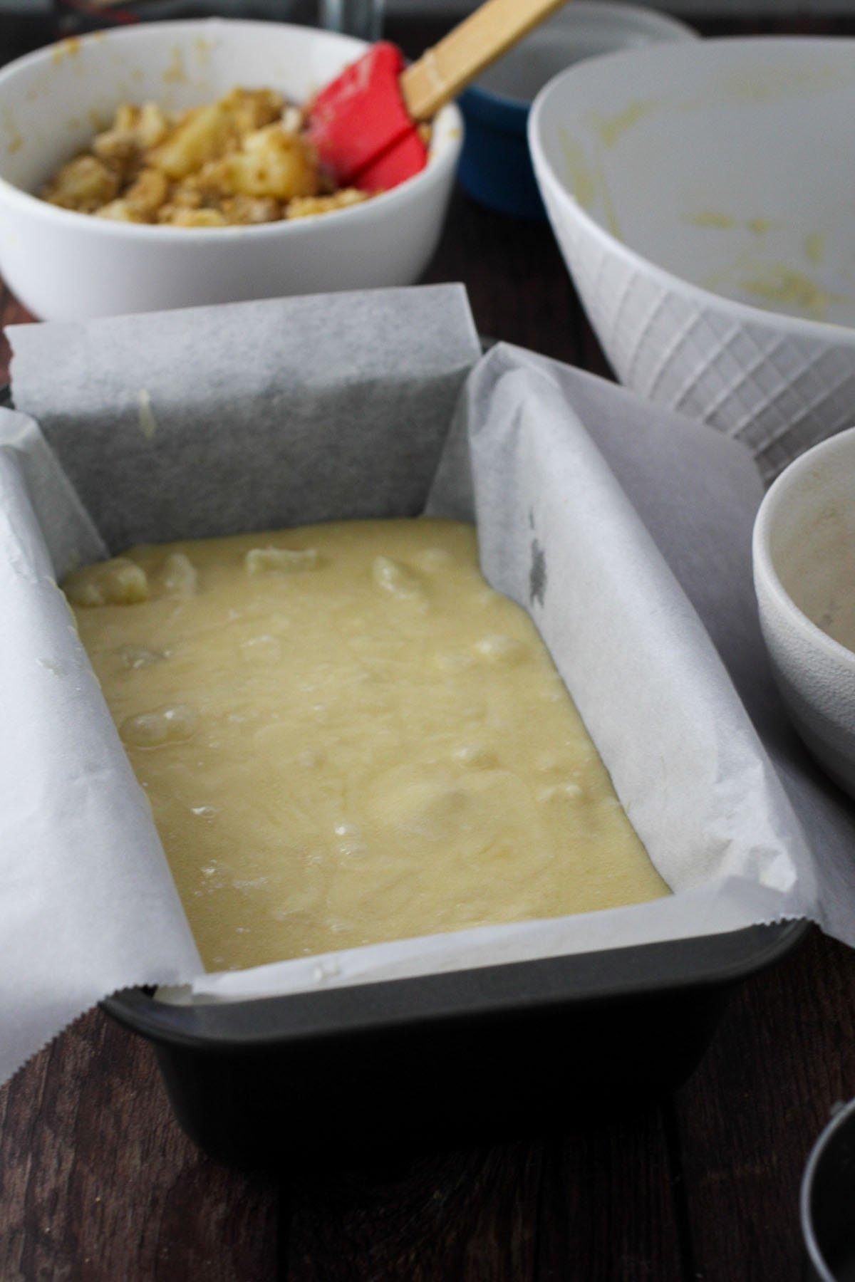 A close-up shot of the batter being poured over the pineapple in the baking pan.