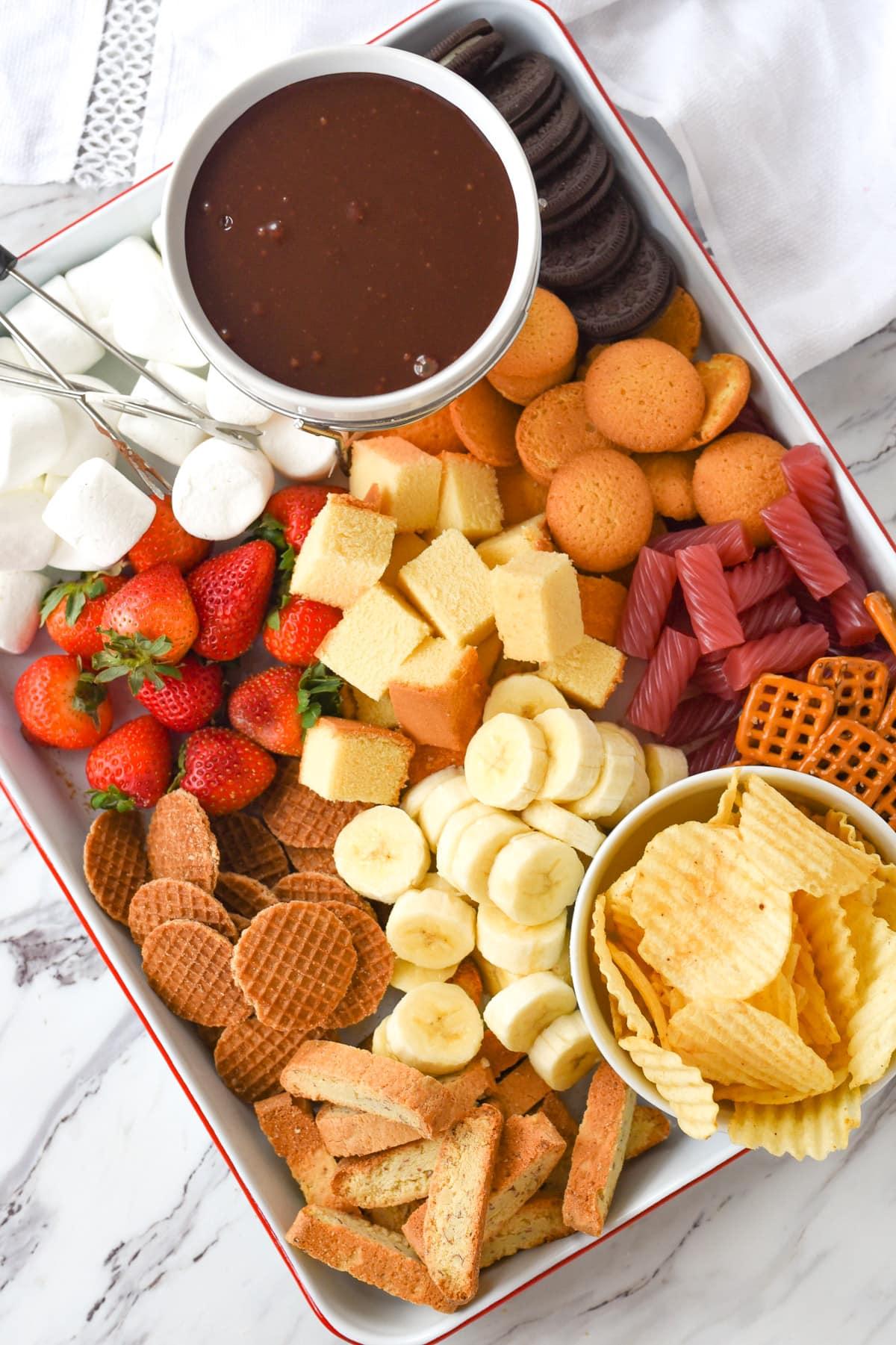 A steaming pot of chocolate fondue with various dippers arranged around it.