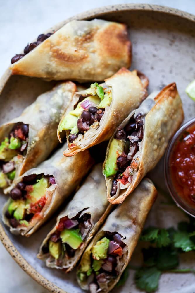 hands rolling avocado and black bean spring rolls
