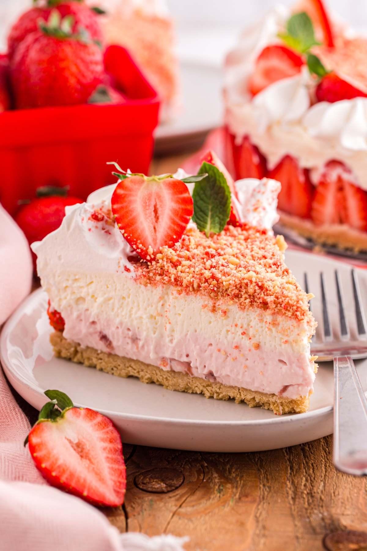 A slice of Strawberry Shortcake Cheesecake with fresh strawberries on top
