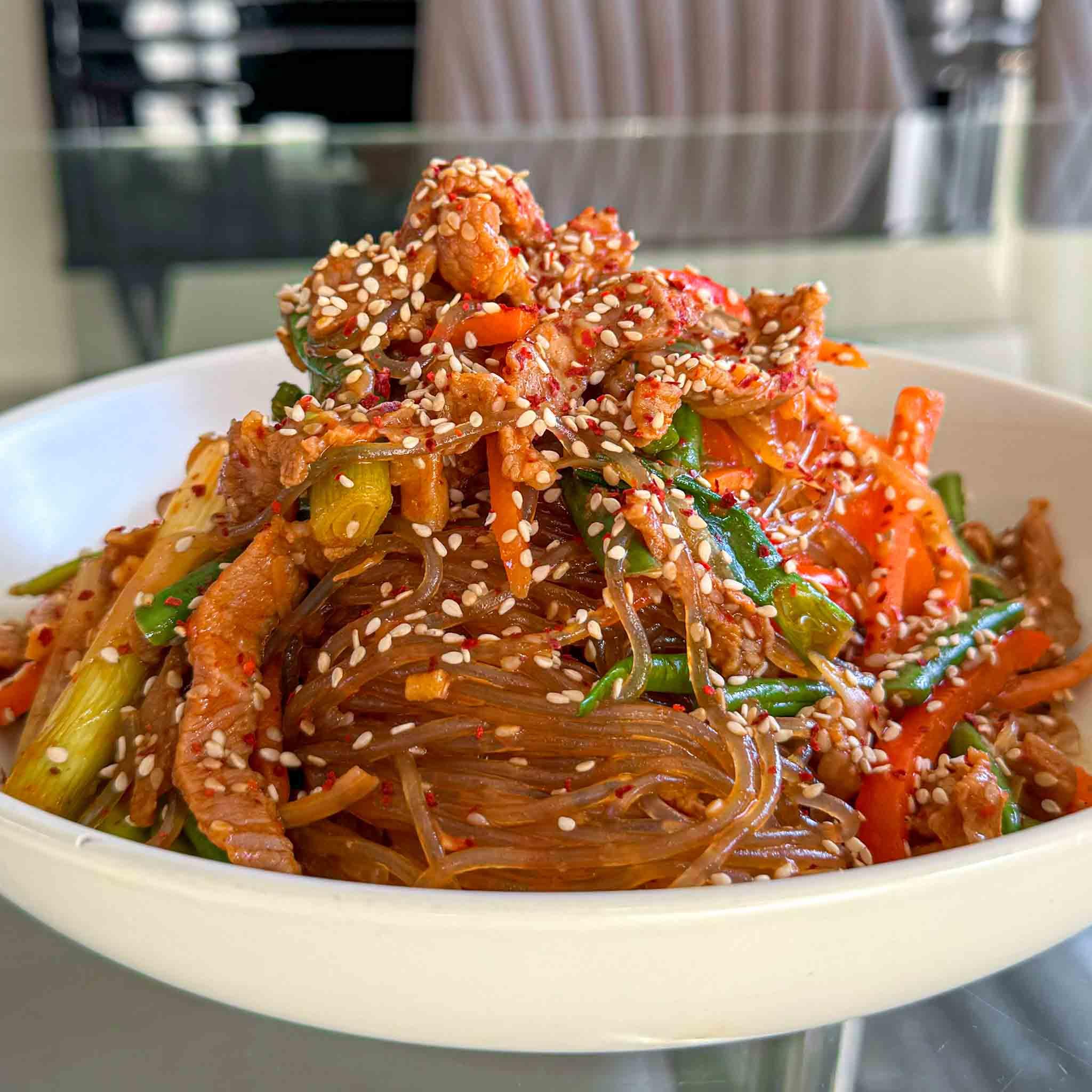 A vibrant, close-up shot of a delicious Spicy Asian Noodle dish, showing the noodles, pork, vegetables, and sauce