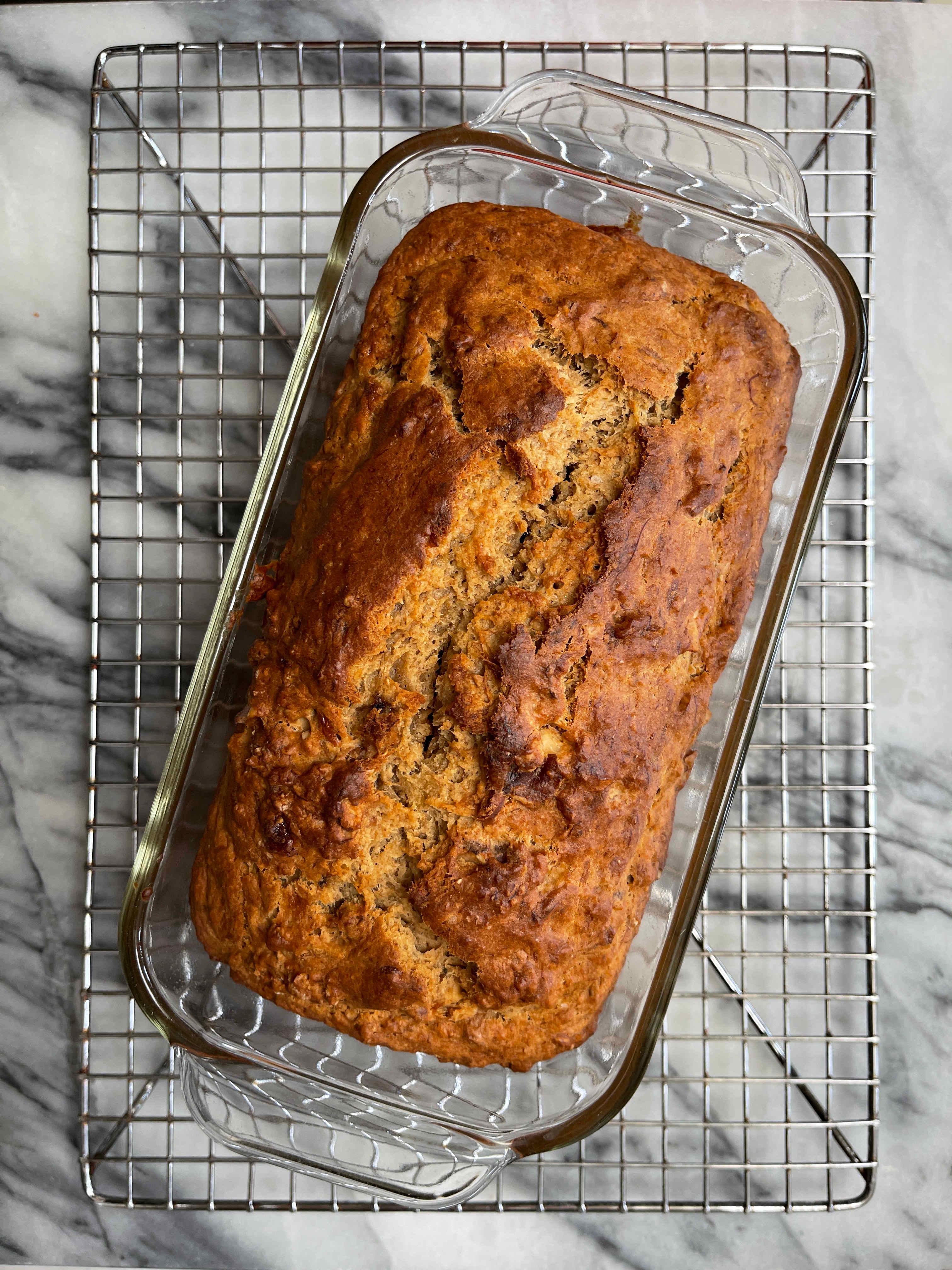 Close-up shot of a loaf of zero-waste banana bread cooling on a wire rack, showcasing its rich color and slightly crinkled top.
