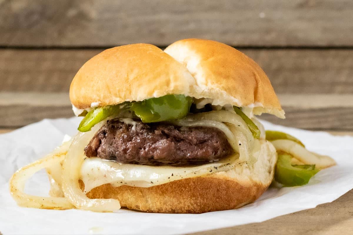 juicy philly cheesesteak burger with provolone drizzle close-up