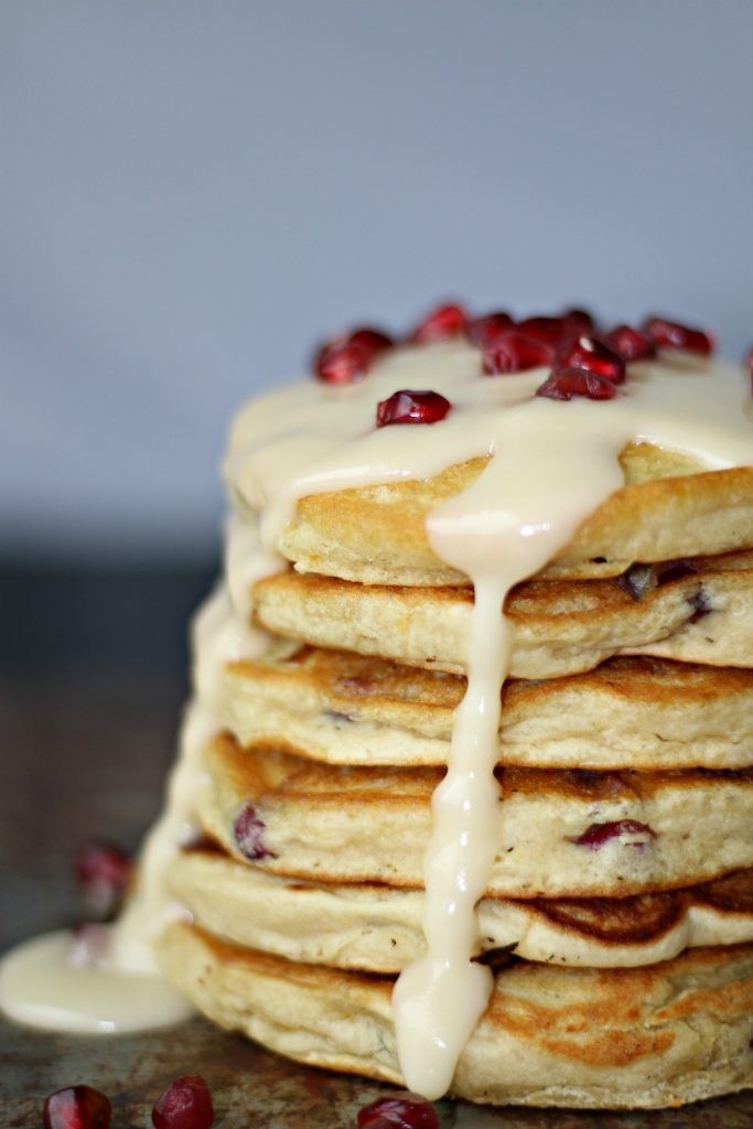 stack of pomegranate pancakes with fresh pomegranates and syrup