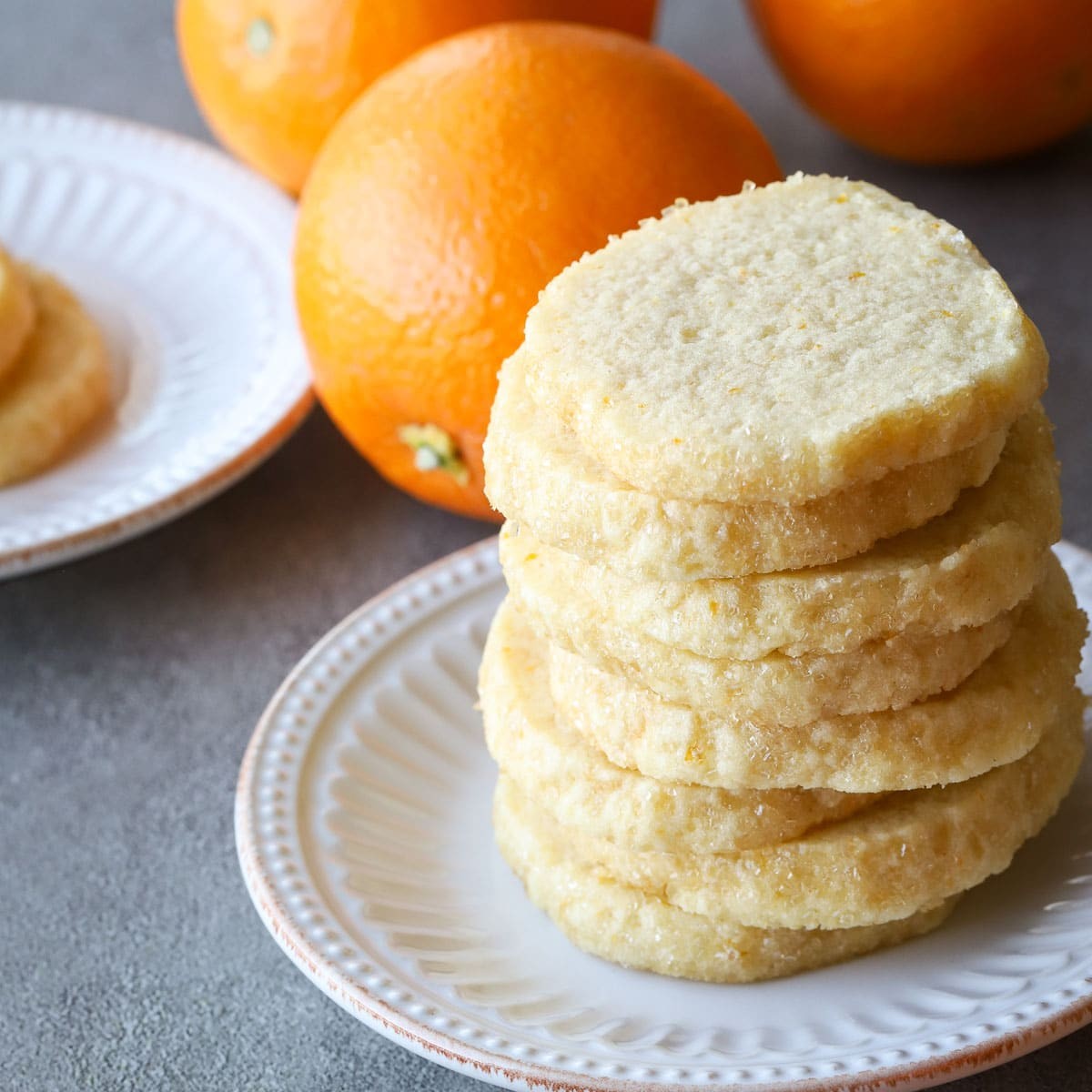 Plate of perfectly baked orange zest cookies with fresh orange slices and zest scattered around, bright and inviting