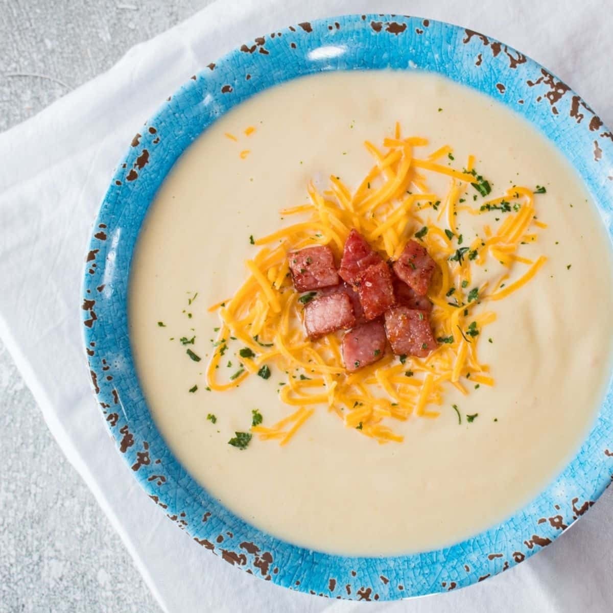 A bowl of hearty keto soup with diced ham and cauliflower rice, garnished with fresh parsley