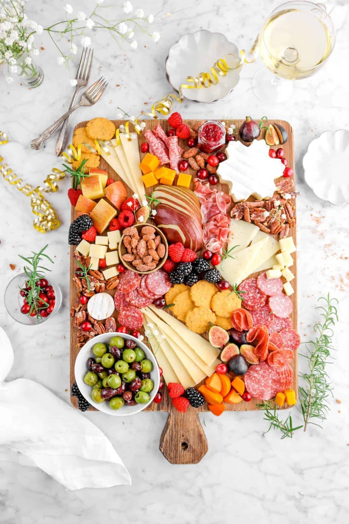 Elegant charcuterie board with baked camembert, fruits, crackers, and meats, overhead shot