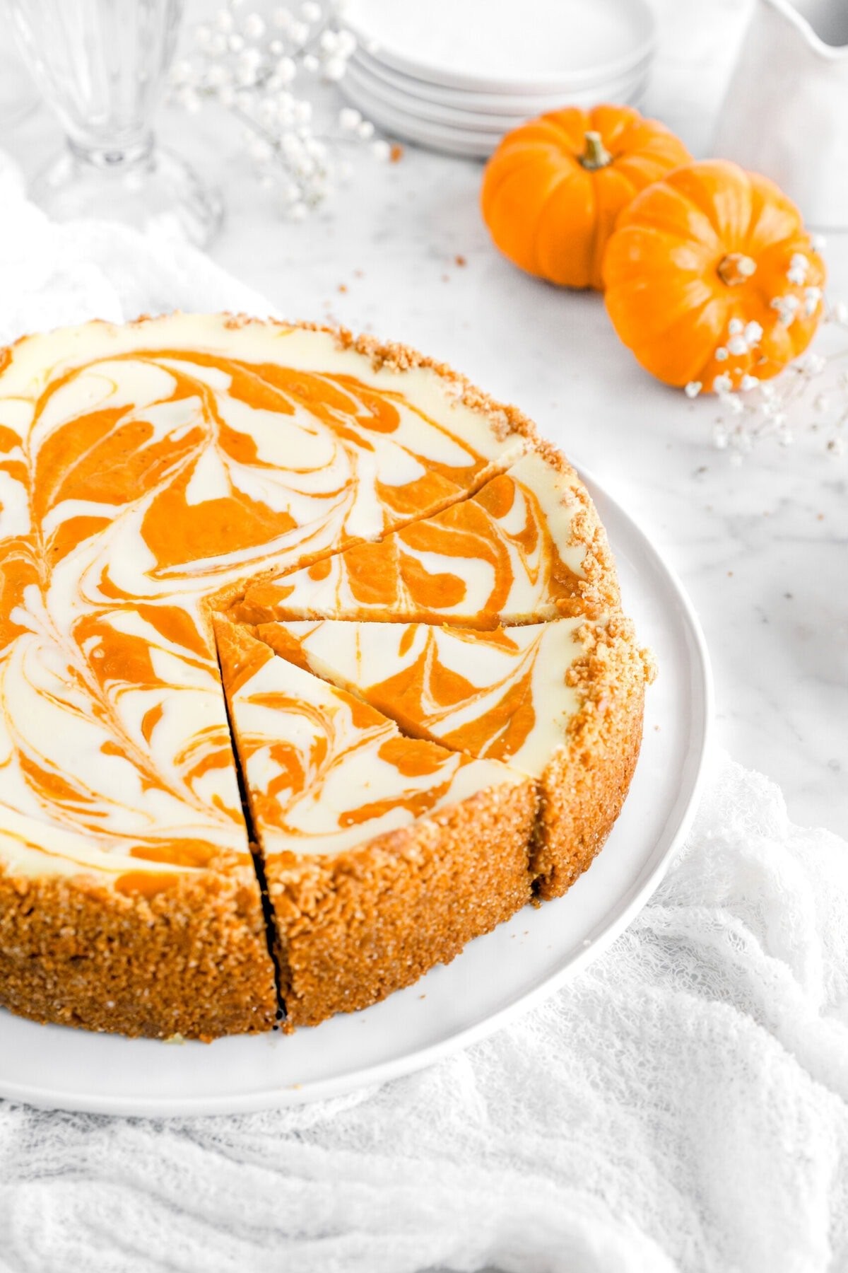 Gourmet pumpkin cheesecake with a beautiful cream cheese swirl on top, autumn colors in background