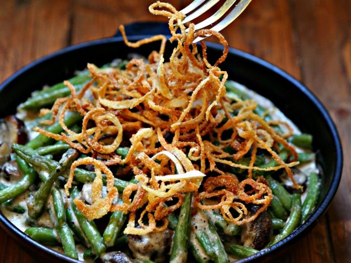 Rustic cast iron skillet green bean casserole, golden brown crispy onions, fresh herbs