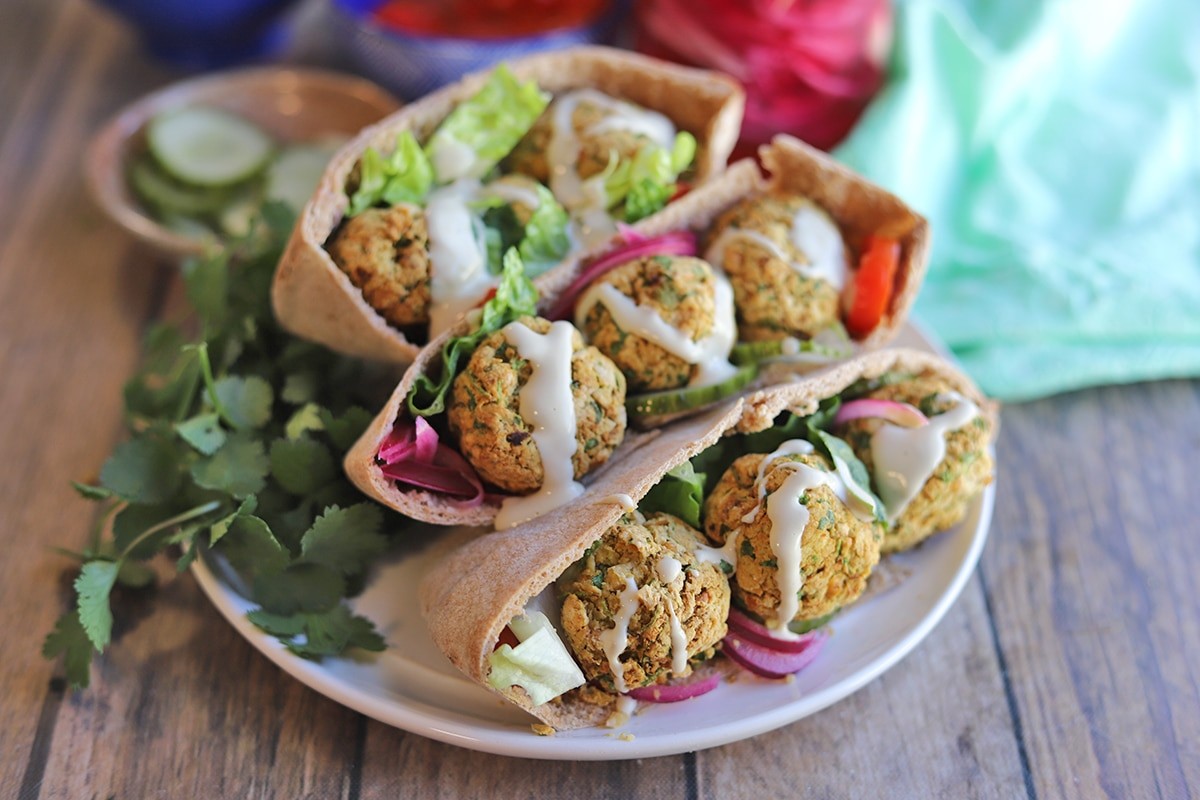 A delicious pita pocket filled with fried plantains and crispy falafel, garnished with fresh herbs.