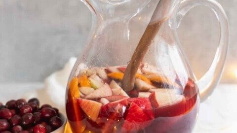 vibrant ruby red sangria with fresh fruit and ice in a decorative pitcher, holiday setting