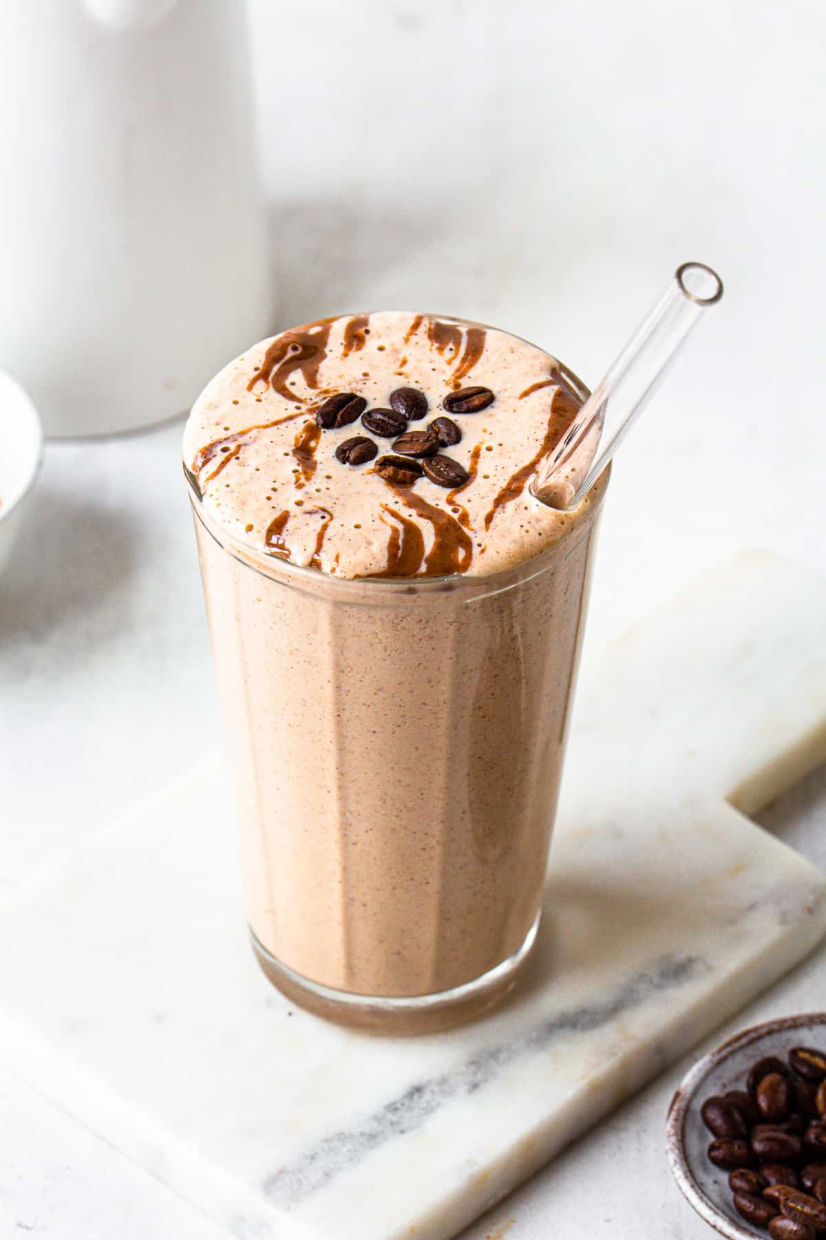coffee almond smoothie in a glass with almonds and coffee beans