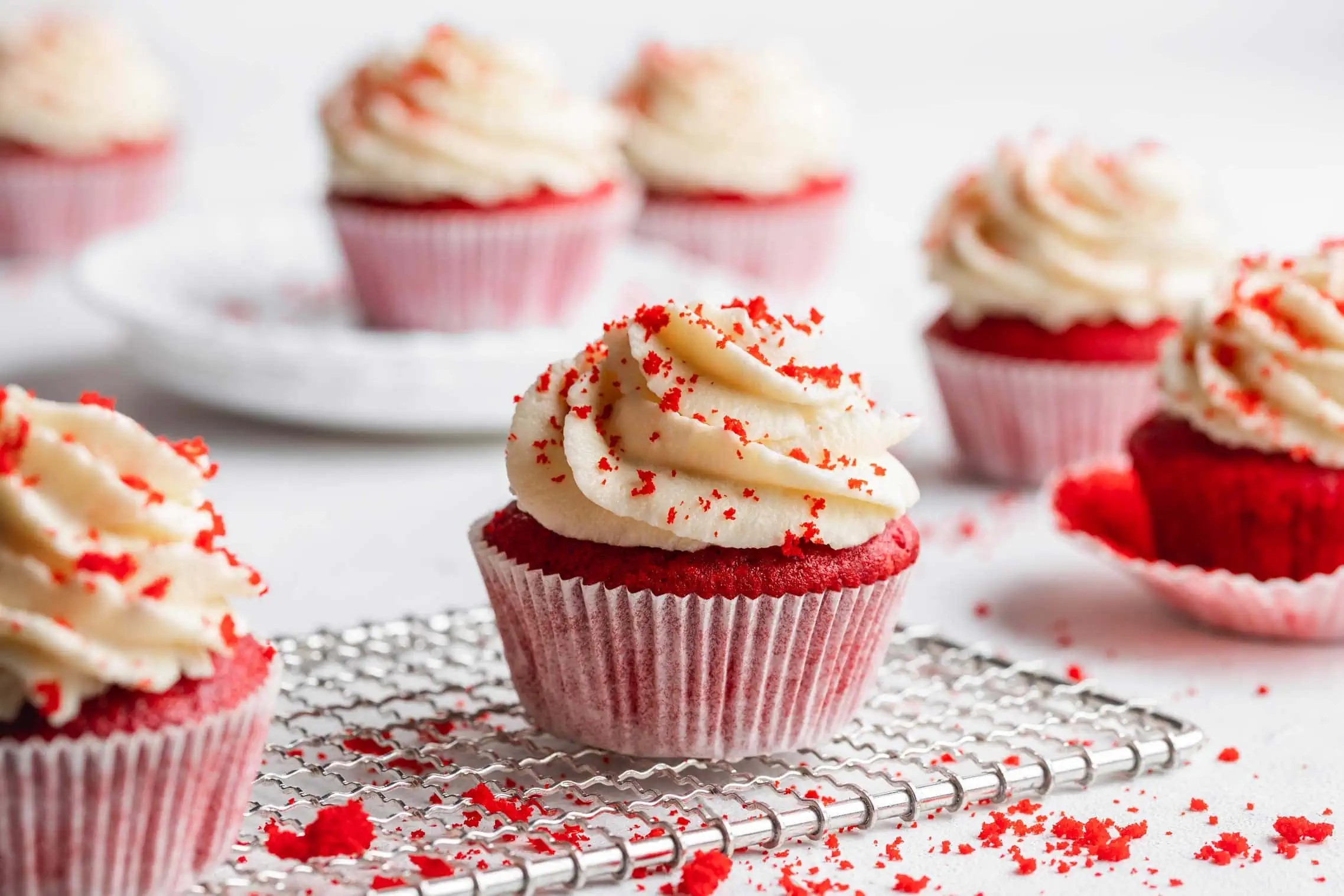 red velvet cupcakes with white frosting and sprinkles