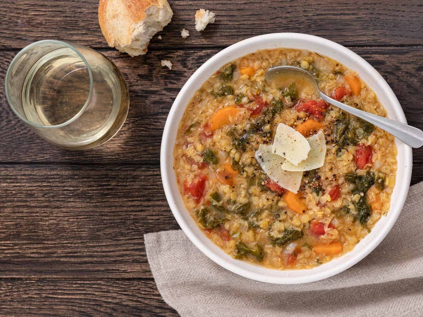 steaming bowl of rustic lentil vegetable stew with crusty bread