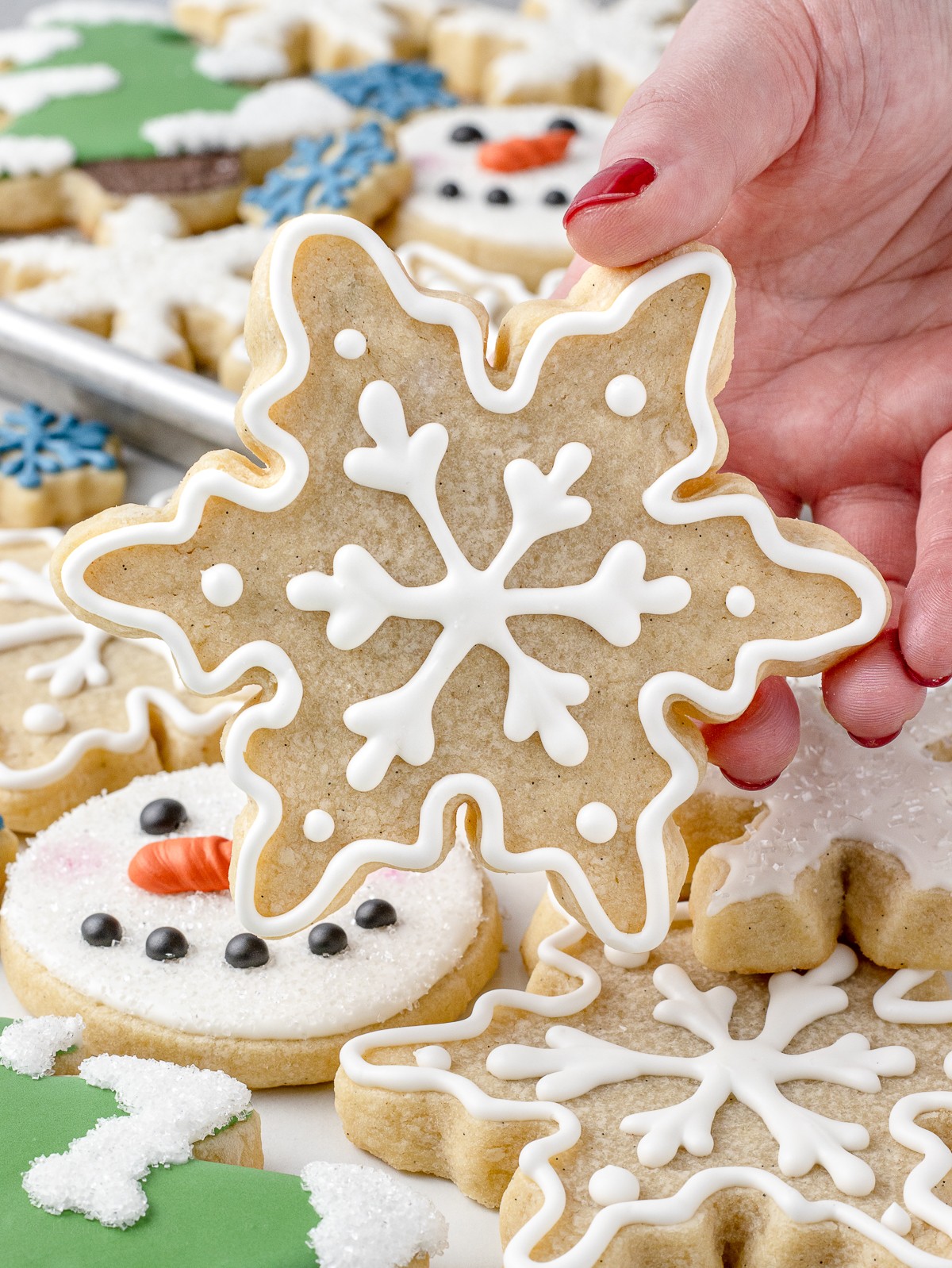 beautifully decorated vanilla sugar cookies with intricate hand-piped royal icing designs on a rustic wooden table, soft lighting