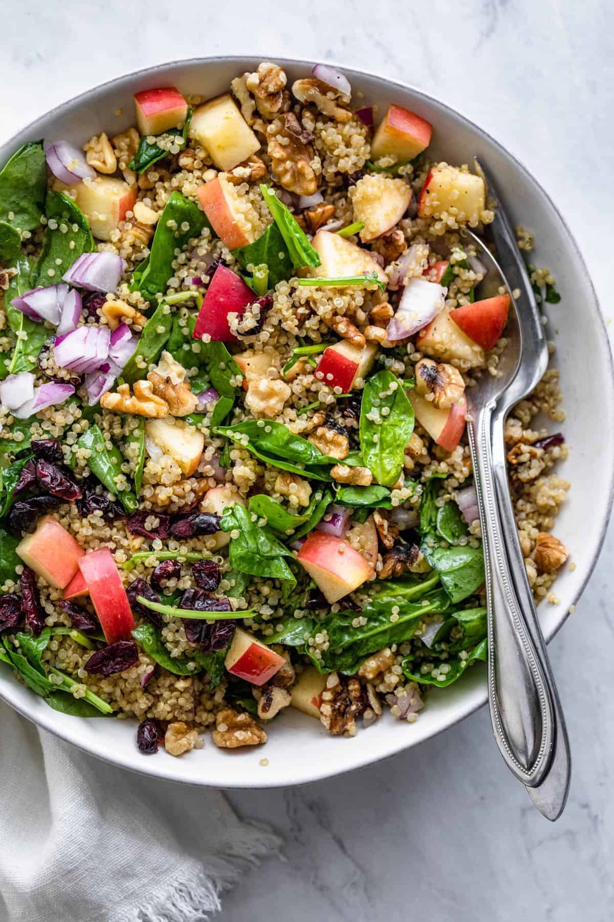 quinoa salad with apples and walnuts on a rustic wooden table
