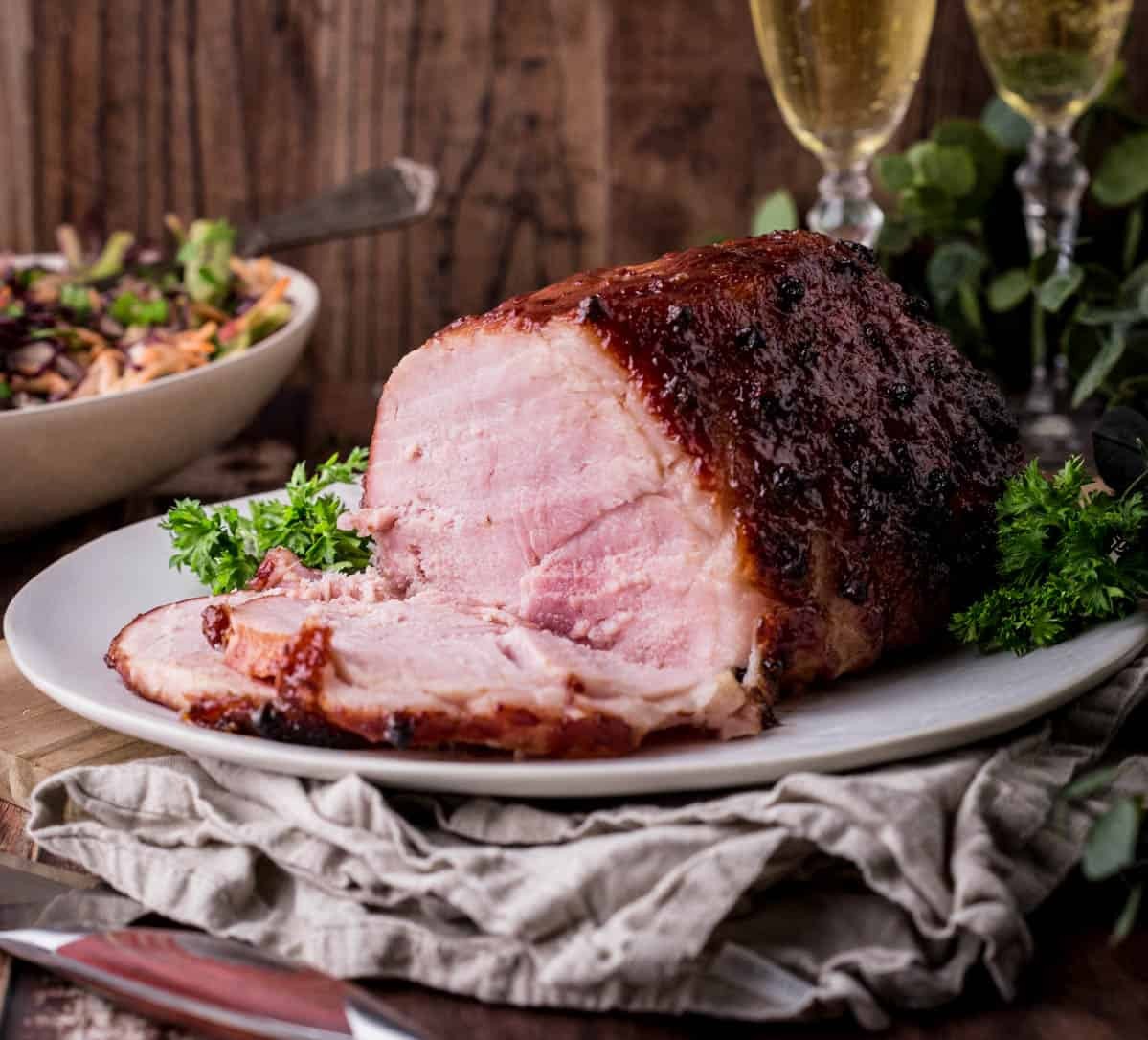 Close-up shot of a glistening coffee-rubbed Christmas ham with a rich molasses glaze, garnished with fresh cranberries