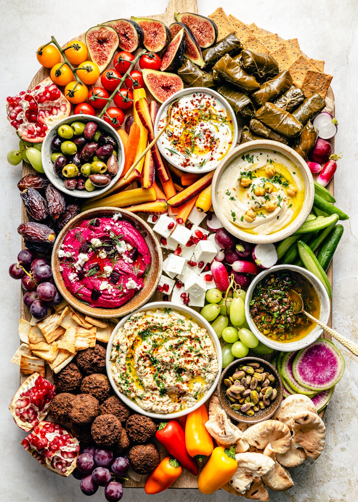 Vibrant Mediterranean mezze board with assorted dips, olives, and fresh vegetables on a wooden platter