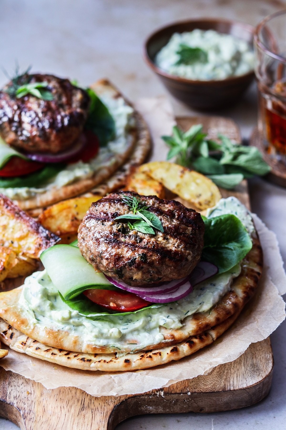 Greek lamb burgers with tzatziki sauce and feta cheese on a wooden board