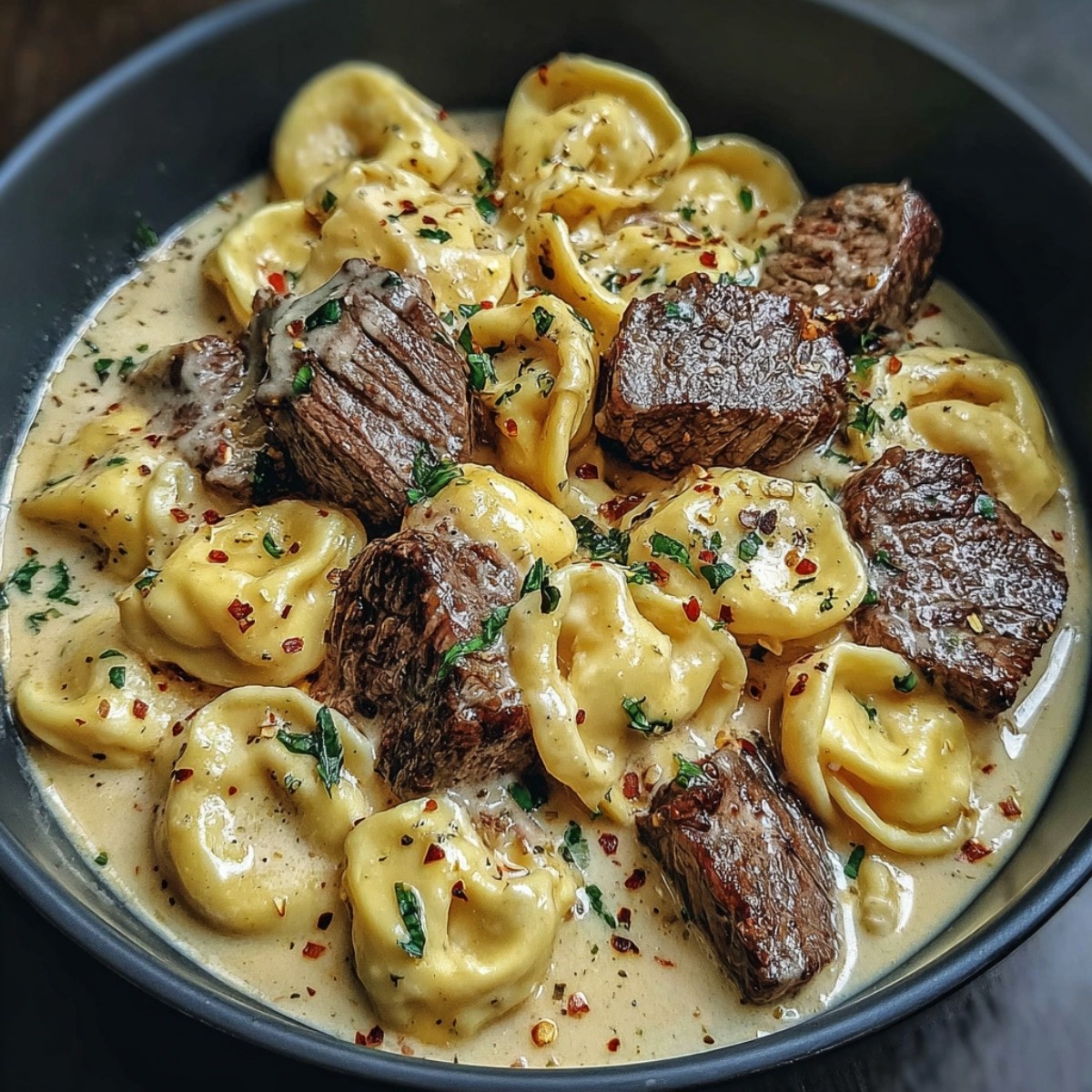 Delicious garlic steak and cheese tortellini skillet close up, garnished with fresh herbs