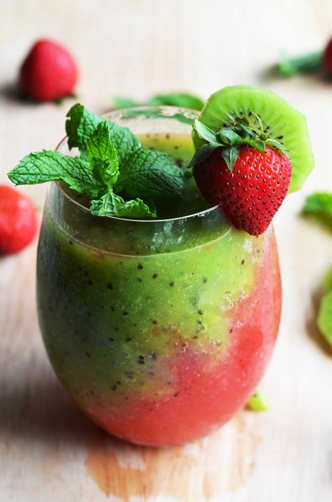Vibrant pink and green strawberry kiwi smoothie in a glass with fresh fruit garnishing