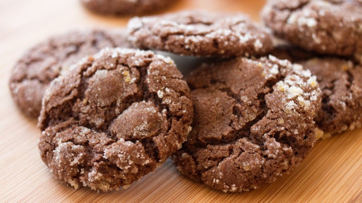 A plate of shiny chocolate orange cookies with fresh orange zest, beautifully styled, warm kitchen light