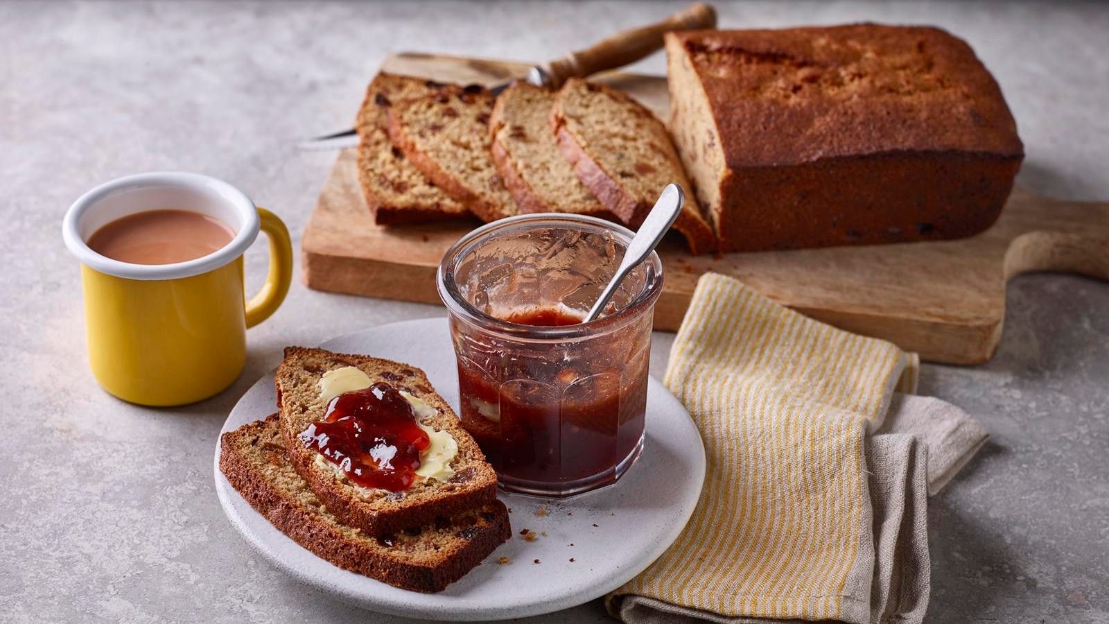 a freshly baked lingonberry tea loaf on a wooden board, lingonberries scattered around