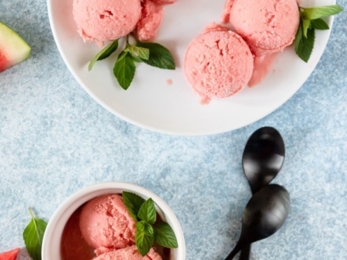 close-up of vibrant watermelon sorbet in a glass bowl, garnished with mint leaves
