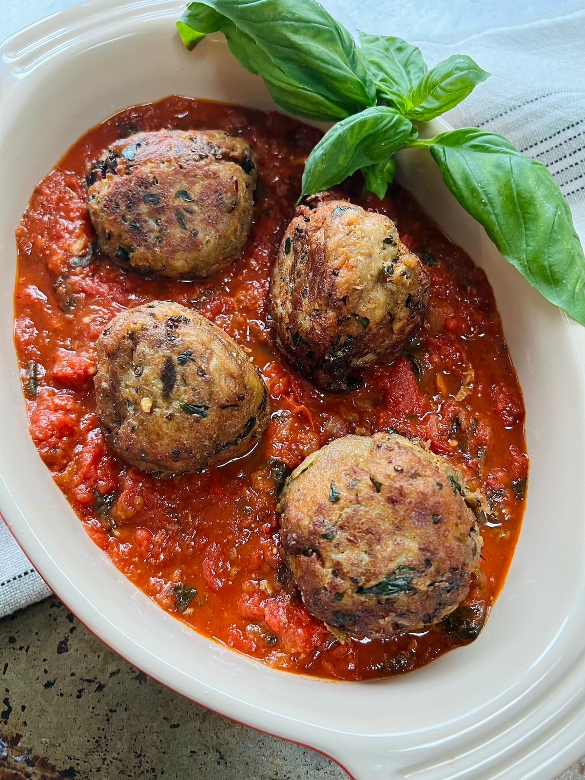 Close-up shot of delicious eggplant and parmesan plant-based meatballs on a plate, garnished with fresh basil