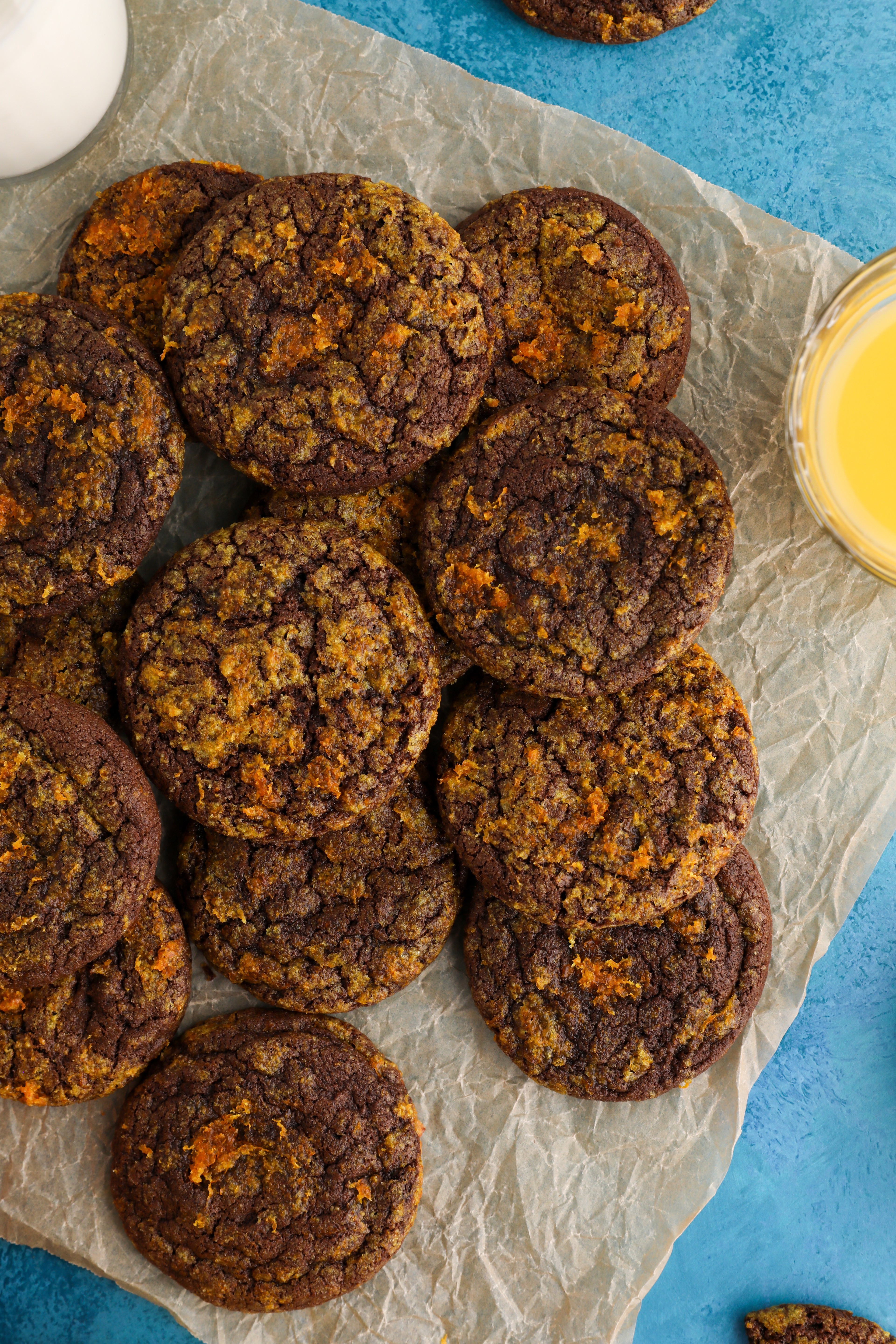 vibrant close-up of glossy chocolate orange cookies on a cooling rack, with orange zest scattered around