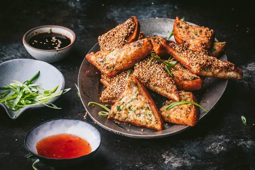golden crispy sesame shrimp toast appetizer on a platter with sweet chili dipping sauce