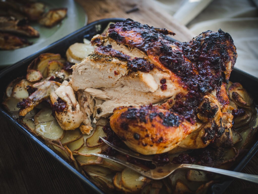 golden brown roast chicken with lingonberry herb butter, garnished with fresh herbs