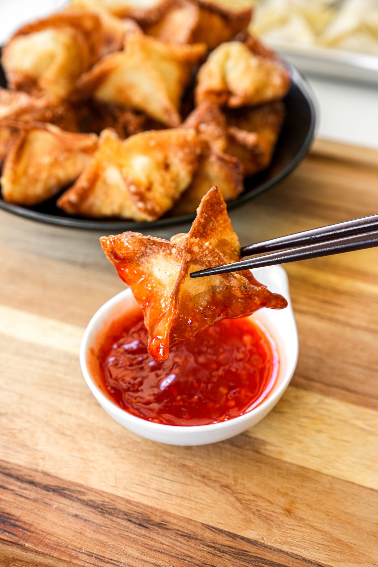 golden crispy chicken wontons platter with sweet chili dipping sauce, close-up, top view